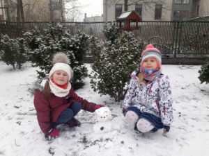 Dwie dziewczynki pozujące przy śnieżnym bałwanku 